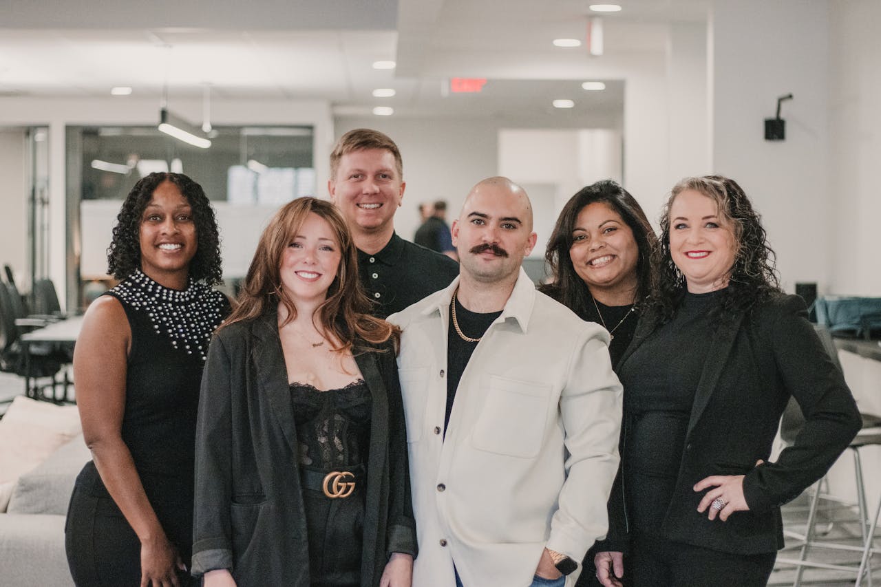 Diverse group of professionals posing confidently in modern office environment.